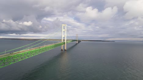 close aerial forwarding drone shot of the mighty mac, mackinaw, bridge, partly cloudy day above the water