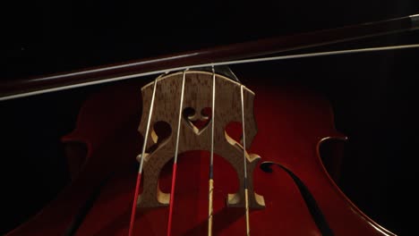 macro artístico en cámara lenta del maestro artesano luthier tocando con un arco en un violín o violonchelo hecho a mano