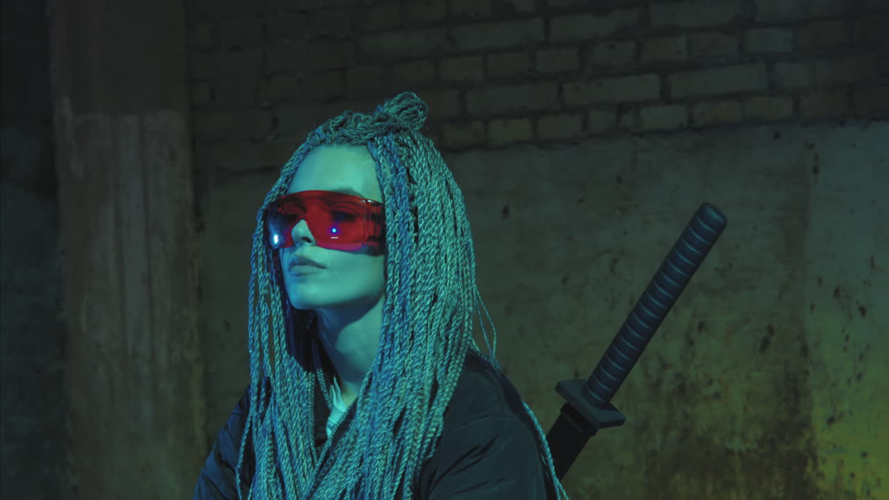 chica con dreadlocks y katanas en gafas rojas posando contra una pared de ladrillo de neón