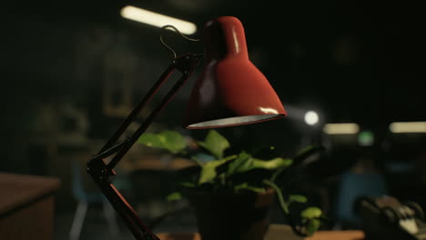 lámpara de escritorio roja en un escritorio de madera con una planta