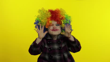 una niña payasa con una peluca colorida haciendo caras tontas. divirtiéndose, cantando, bailando. halloween