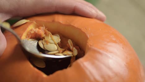 removing seeds from a ripe fresh pumpkin with a spoon