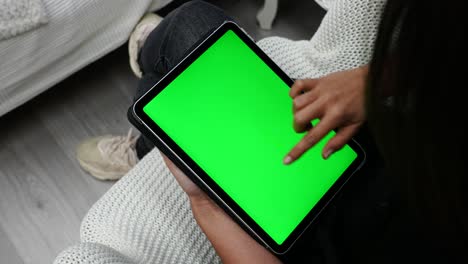 mano femenina y dedo en la tableta de pantalla verde deslizando varias páginas, cierre la vista superior