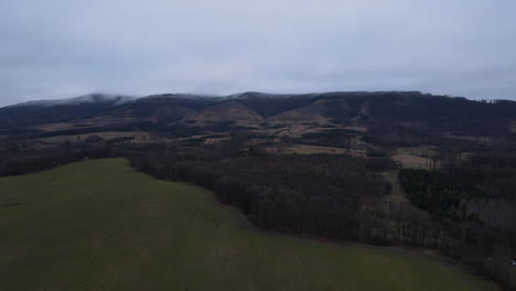 Fly-over-the-landscape-with-the-forest-below-you-in-the-background-of-snowy-hills