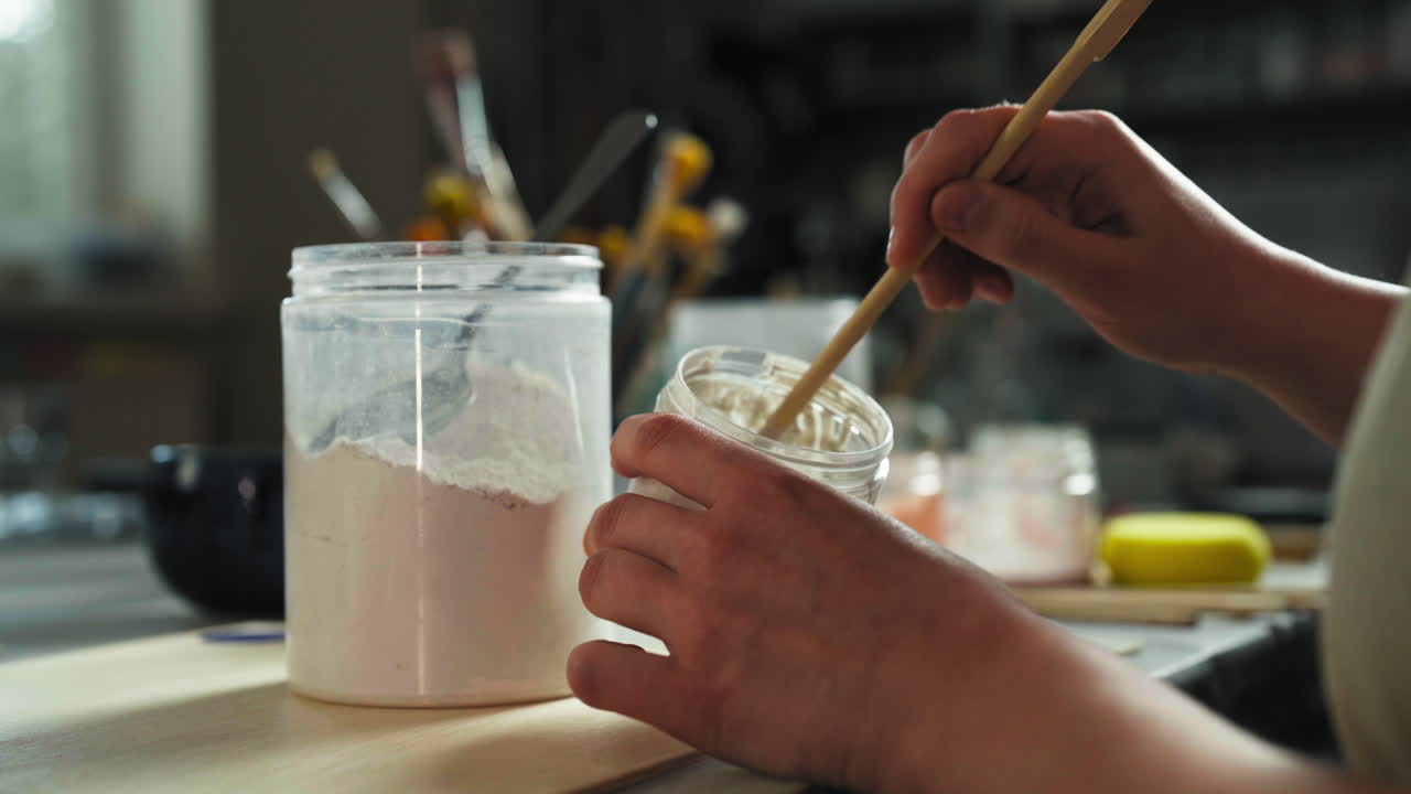 Female Artist Mixing Glaze For Clay Cups At Workshop. closeup shot