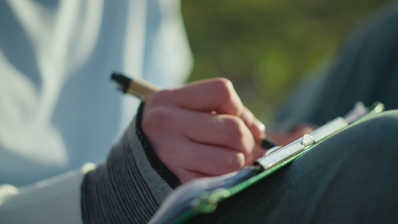 serene woman pens notes amid lush grass, calm female writer records thoughts under sunlight and trees, tranquil woman thoughtfully documents ideas while immersed in peaceful outdoor setting
