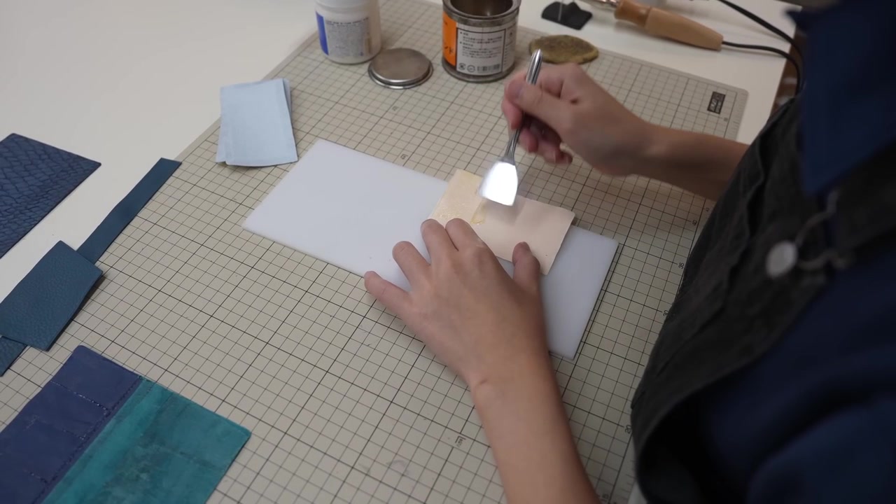 Vakman drukt een lichte leren flap tegen een marineblauw leren paneel