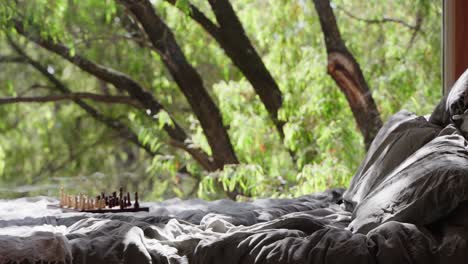 Cinematic-reveal-of-bed-with-chess-board-on-top-inside-tiny-cabin