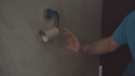 toilet paper is finished in the toilet, the man touches the empty roll with his hand