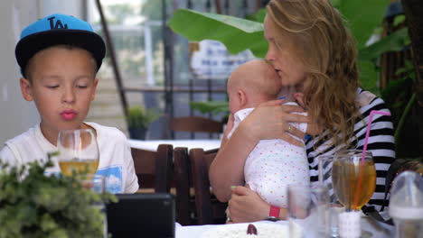 mother with baby daughter and elder son in street cafe