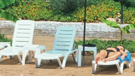 mujer tomando el sol en una silla junto a la piscina