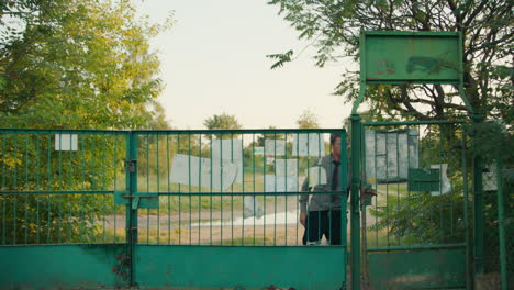 man walking through a green metal gate in a park