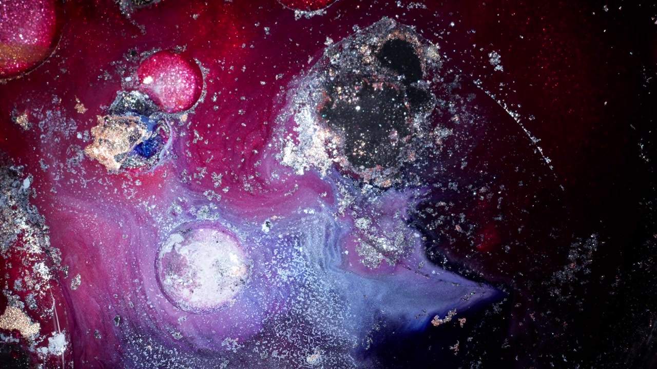 Makrobilde av mørk lilla og rød alkoholblekk som blander seg med metalliske gullpartikler, og skaper en kosmisk galakse-effekt i en stemningsfull, filmatisk studioinnstilling.