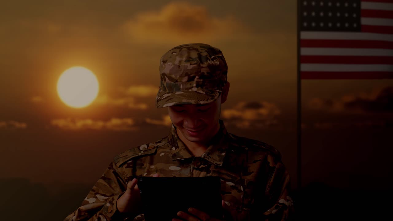 primer plano de un soldado asiático usando una tableta mientras está de pie con la bandera de los estados unidos, hora del atardecer