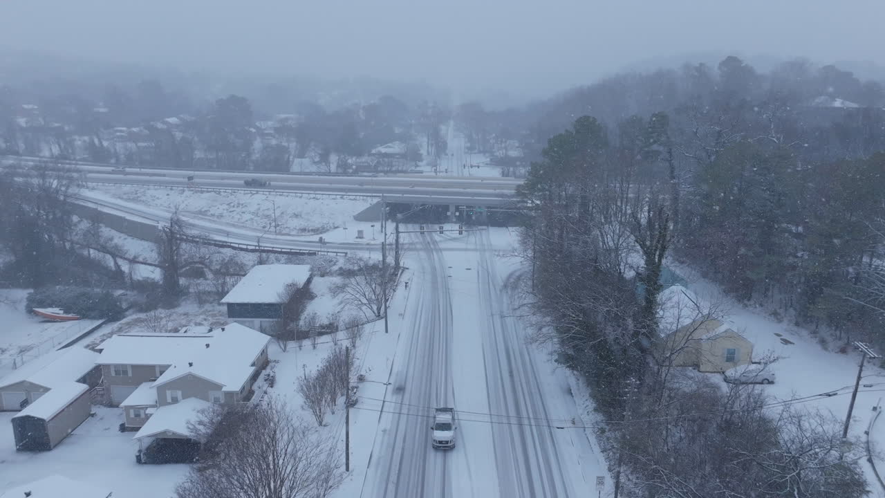 Aerial footage flying above a road that intersects with a highway in Chattanooga, TN during a snowstorm.