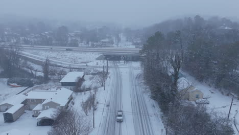aerial footage flying above a road that intersects with a highway in chattanooga, tn during a snowstorm.