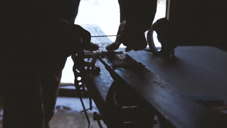 Slow-motion-shot-of-person-waxing-skis,-scraping-wax-off-of-ski