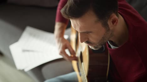 Close-up-video-of-man-practicing-guitar-play-on-sofa