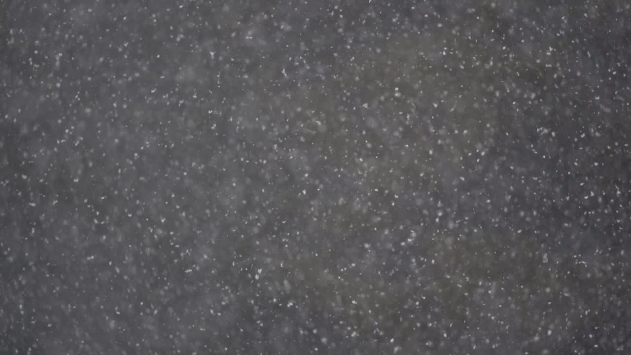una fuerte tormenta de nieve cayendo en cámara lenta con un fondo oscuro borroso