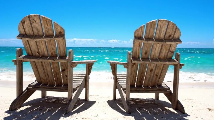 Serene strandscène met twee identieke houten ligstoelen met uitzicht op kalme turquoise golven onder een helderblauwe lucht op een prachtige zonnige dag