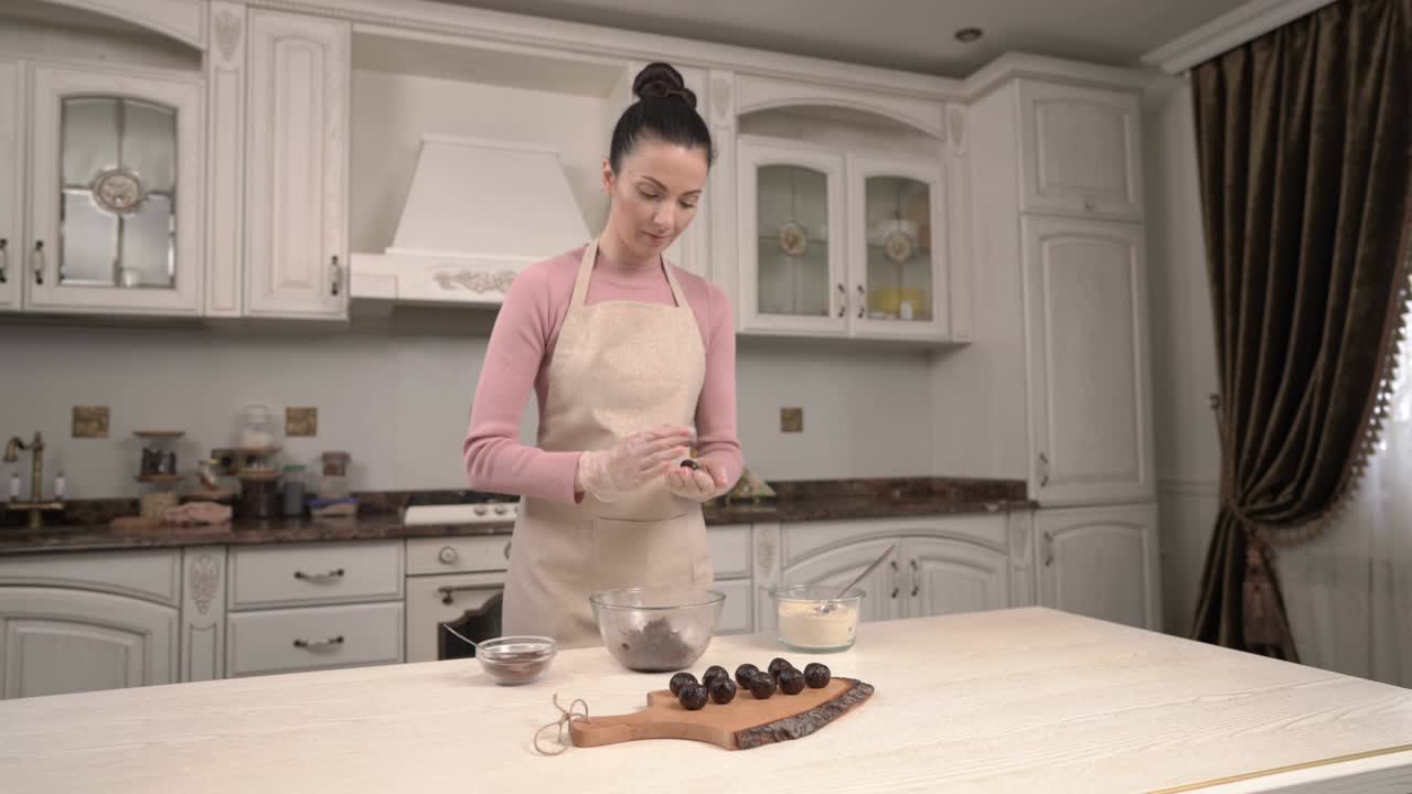 Giovane casalinga in cucina che prepara dolcetti al cioccolato e li adagia su un tagliere di legno. Concetto di preparazione di dolci fatti in casa.