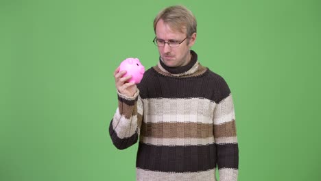 blonde handsome man holding piggy bank and ready for winter