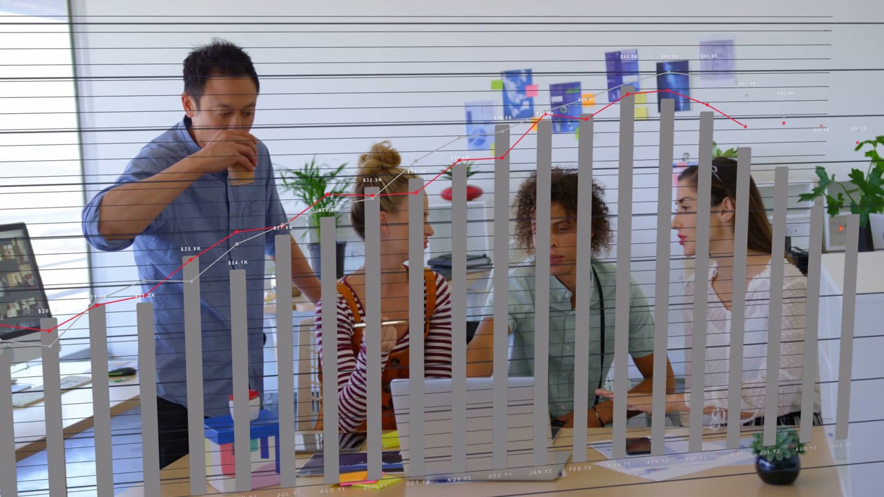 Four colleagues leaning at laptop, center using trackpad causing business chart overlay over models