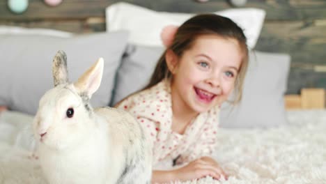 Glückliches-Mädchen,-Das-Mit-Kaninchen-Auf-Dem-Bett-Spielt