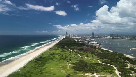 Aerial-view-of-a-nature-corridor-leading-to-a-towering-urban-city-skyline