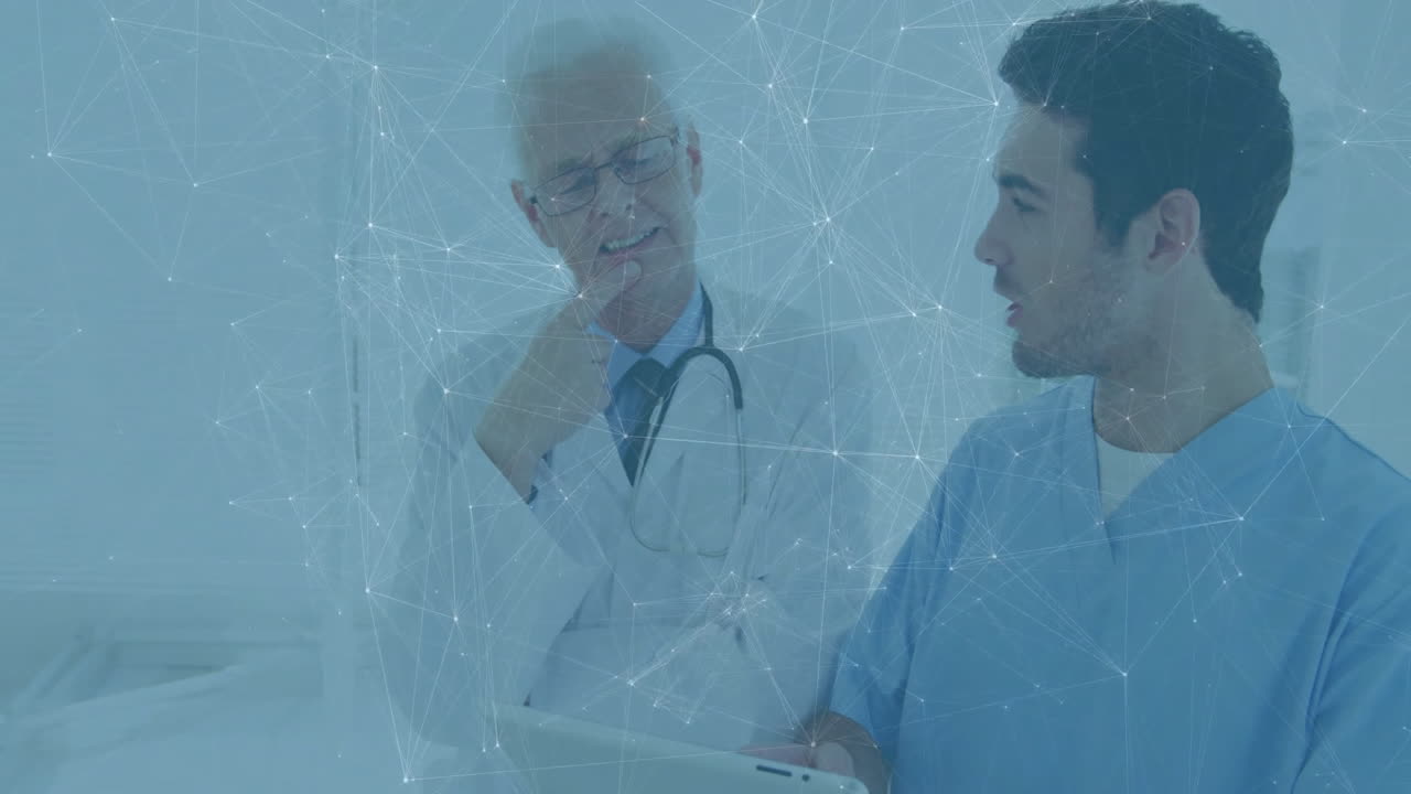 Mature male doctor and younger clinician consulting on tablet in clinic, showing network overlay