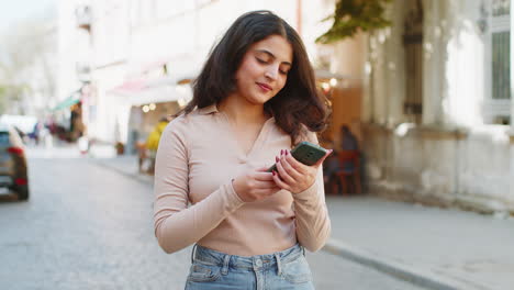 Indian-woman-use-mobile-smartphone-celebrating-win-good-message-news-outdoors-on-urban-city-street