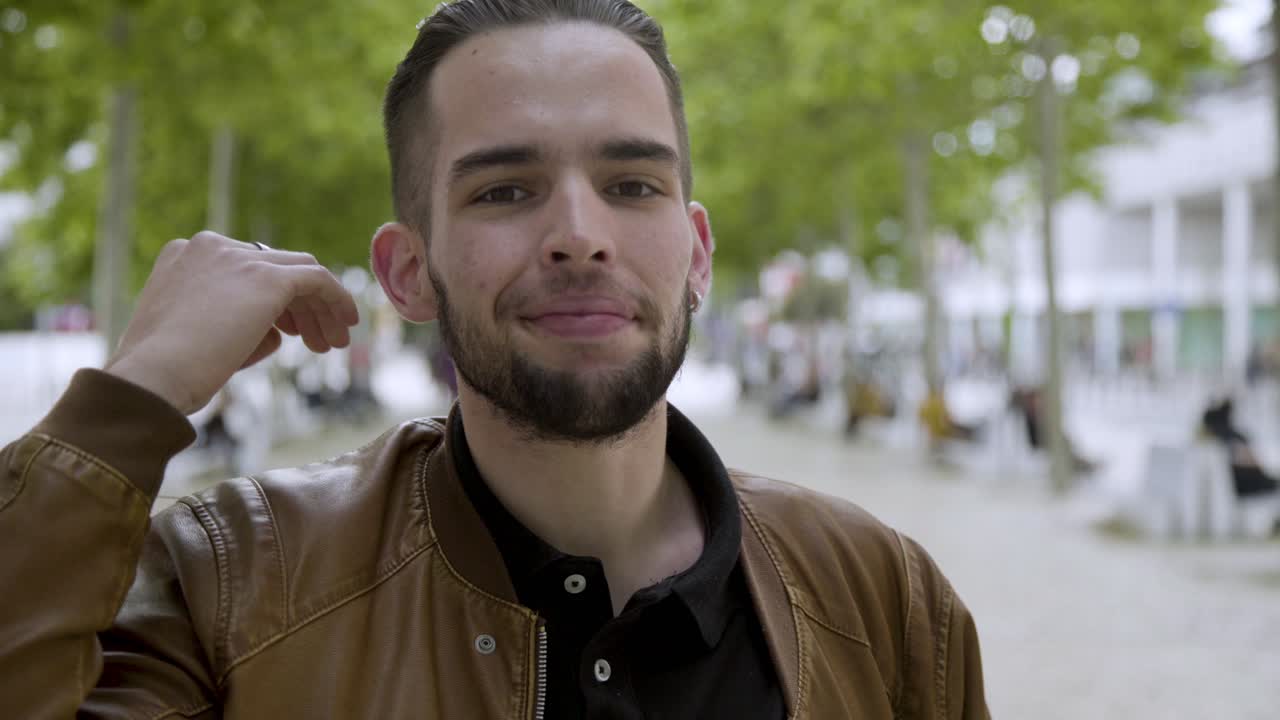 un primer plano de un joven sonriente con una perforación de barba de frotamiento.