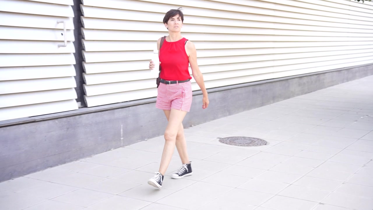 自由奔放で活気に満ちたエネルギーを放ちながら、カジュアルな夏の服装で歩いている若い女性。