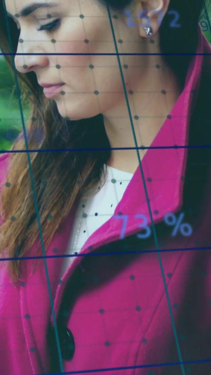 Video verticale: Donna con cappotto magenta che tiene una tazza, con la telecamera che esegue una panoramica rivelando il profilo mentre aggiorna una griglia di dati.
