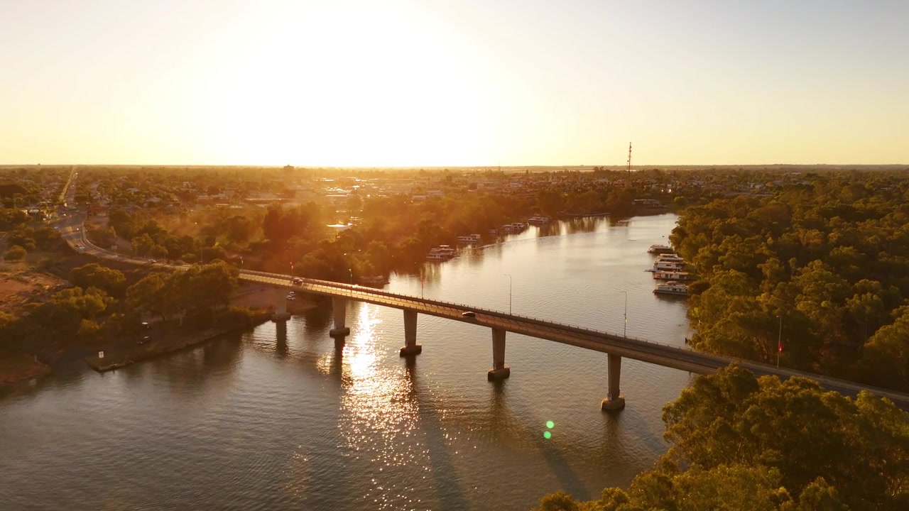 Ponte di Mildura che si estende sul fiume Murray con il caldo bagliore del tramonto e l'acqua tranquilla che scorre sotto, ripresa aerea orbitale