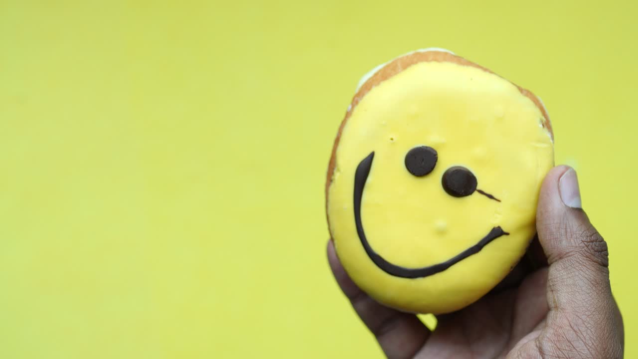 웃는 얼굴의 노란색 도을 들고 있는 손