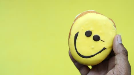 mano con una cara sonriente rosquilla amarilla