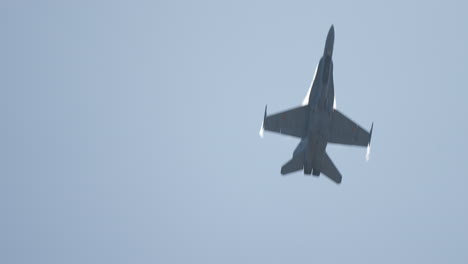military jet aircraft flying fast above with visible aerodynamic condensation as it passes overhead