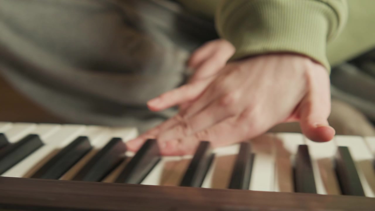 Low-angle view of hands actively playing piano keys with visible finger motion, pressed notes, glossy black and white keyboard, and focused performance energy in warm indoor setting
