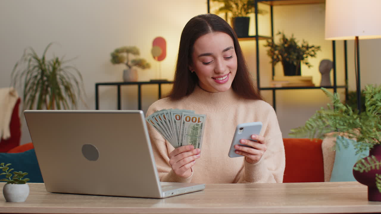 Smiling happy woman counting money cash and use laptop pc calculate domestic income earnings at home