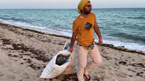 man cleaning up trash on a beach
