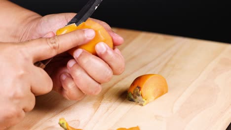 hands carefully peel a ripe persimmon fruit