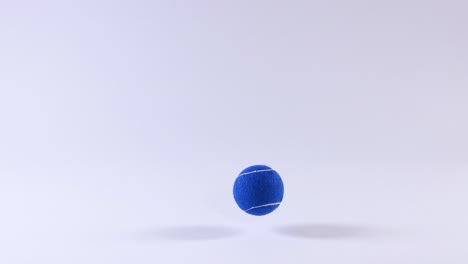 a blue tennis ball bounces on white surface