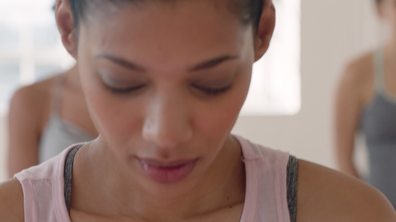 portrait beautiful mixed race woman in yoga class looking curious learning poses enjoying healthy lifestyle practicing with group of women in fitness studio