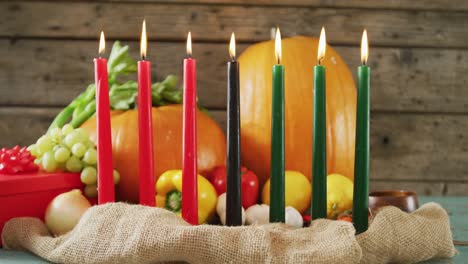 Composition-of-seven-lit-candles-and-halloween-pumpkins-and-vegetables