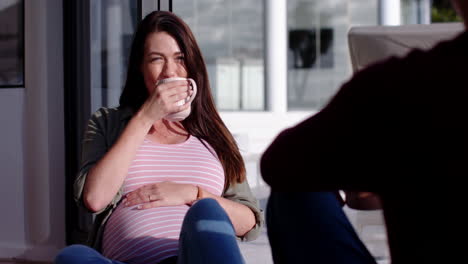 pregnant woman drinking coffee and relaxing with partner at home