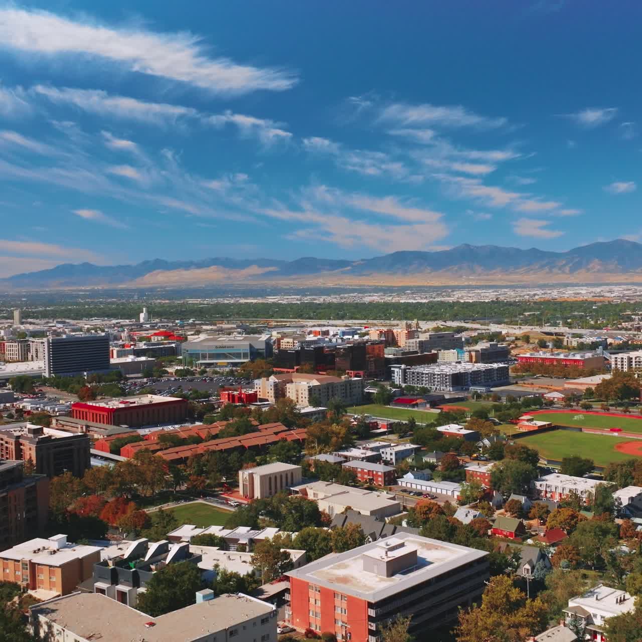 Medley panorama of amazing sunny Salt Lake City in Utah, USA. Vast city scenery with mountains at backdrop. Spindrift clouds in the sky over the urban landscape