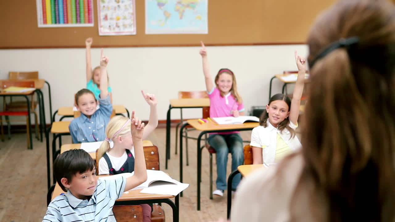 Pupils raising their fingers in front of the teacher