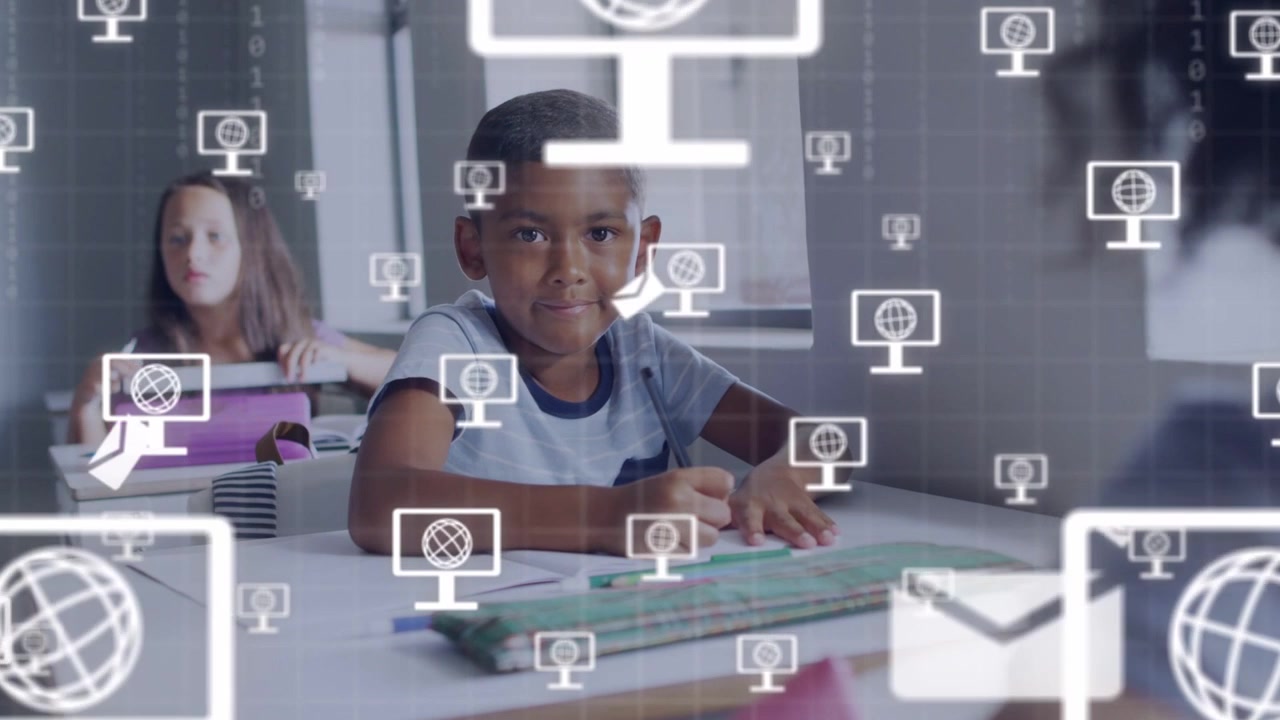 Boy writing and glancing in classroom, starting computer and envelope icons multiplying for edtech