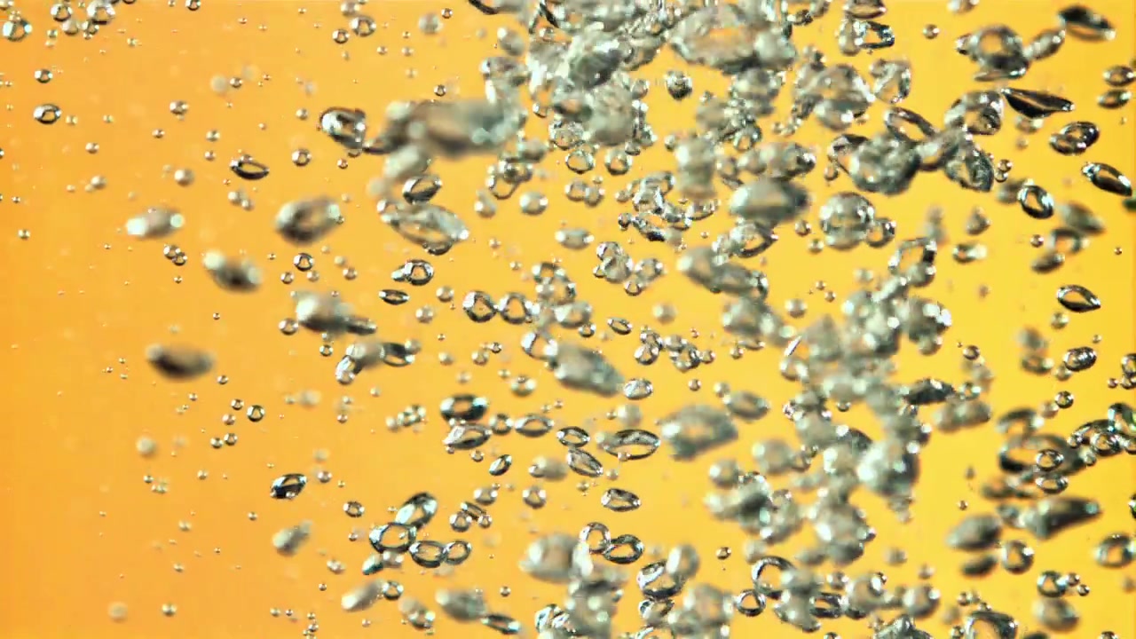 Bolle d'aria trasparenti che salgono in un liquido giallo dorato